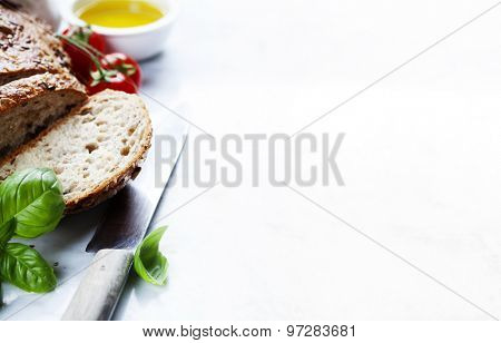 Tomato, bread, basil and olive oil on white marble background. Italian cooking, healthy food or vegetarian concept