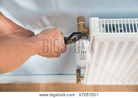 Plumber Fixing Radiator With Wrench