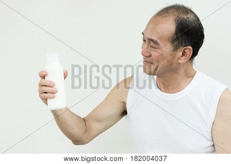 Asian senior man holding bottle of milk.