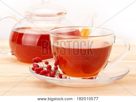Healthy tea with barberries in glass cup on on a white background.