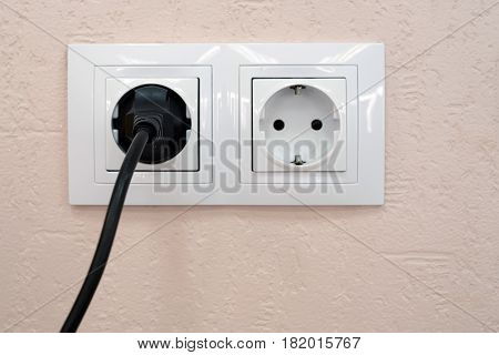 Close-up of two sockets, one with plug and one is free
