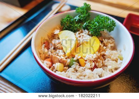 Asian cuisine - Tori tyahan. Fried rice with chicken meat vegetables and radishes in bowl.