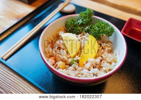 Asian cuisine - Tori tyahan. Fried rice with chicken meat vegetables and radishes in bowl.