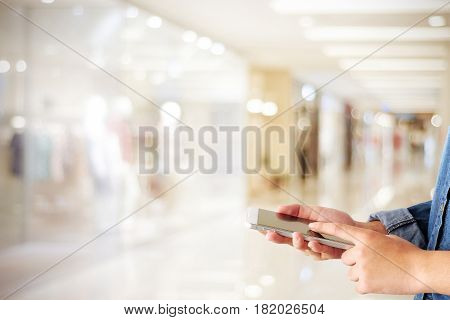 Hand using smart phone over blur store with bokeh light background business and technology concept digital marketing seo e commerce lifestyle social media network