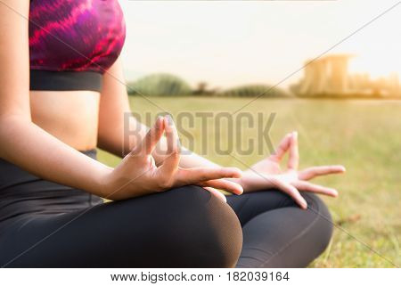 Healthy woman doing Yoga meditation on green lawn in plublic park Singapore.
