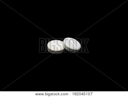 Composition of the white round pills isoltaed on black background