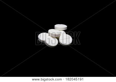Composition of the white round pills isoltaed on black background