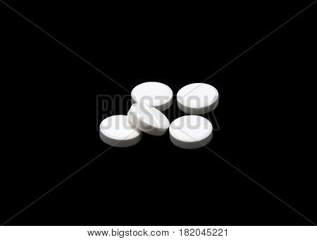 Composition of the white round pills isoltaed on black background