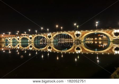 Pont Neuf beautifully illuminated on dark night across Garrone River Toulouse France.