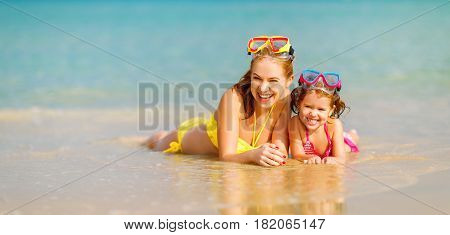 Happy family mother and chid daughter in masks for swimming on the beach in summer