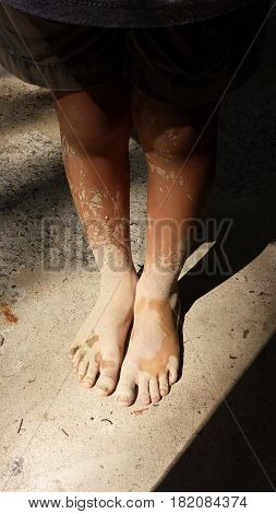 Child's legs dirty with mud from, dramatic shadows