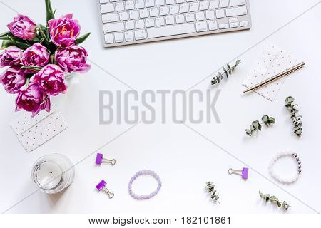 Spring pink flowers on workdesk at home ofiice white background top view mockup