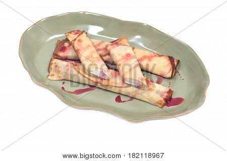 Delicious cheese blintz with raspberry syrup on green plate isolated on white background