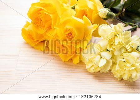 Yellow roses and carnations on a wooden table