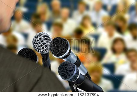 Man giving speech during seminar with blur audiance in background
