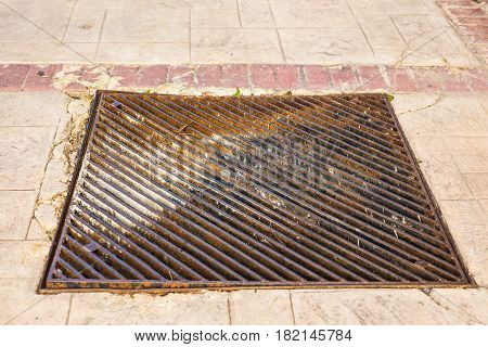 metal storm drain with water running into it.