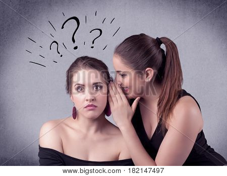 A teenager girl looking confused with drawn question marks above the head, while a girlfriend whispers something in her ear concept.