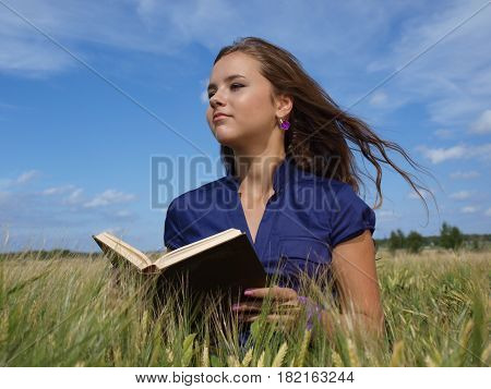 girl in a field with book on her hands