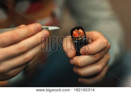Vape After-sales Service Of The E-cigarette. Male Hands Regulate Electronic Cigarette Coils With Pin
