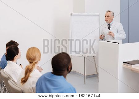 Enjoy teaching young generation. Proficient old involved doctor working and giving the lecture to the interns in the college while explaining the material