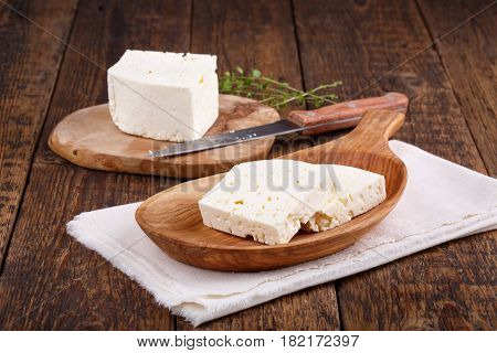 Sliced fresh brined white cheese from cow milk on wooden table
