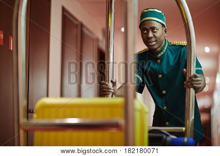 Hall-porter pushing cart with suitcase of new visitor