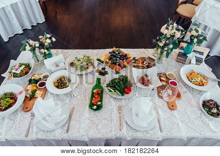 Table setting. Table served for wedding banquet. White napkin on a white empty plate on a dining table