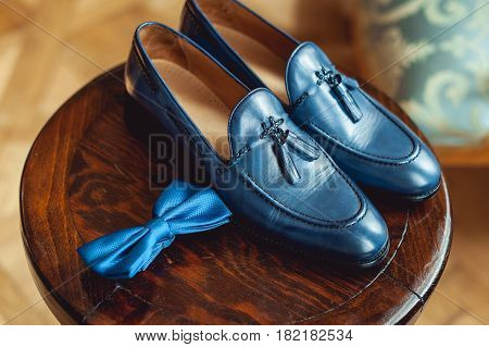 Blue shoes and bow tie on a wooden round stool. Accessory for formal dress. Symbol of elegance and fashion for men. Men's wedding accessories.