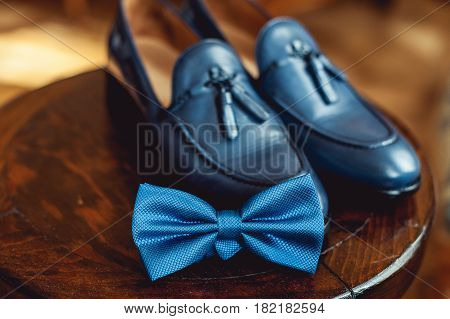 Blue shoes and bow tie on a wooden round stool. Accessory for formal dress. Symbol of elegance and fashion for men. Men's wedding accessories.