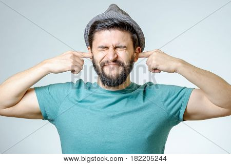 Annoyed Young Man Plugging Ears With Hands