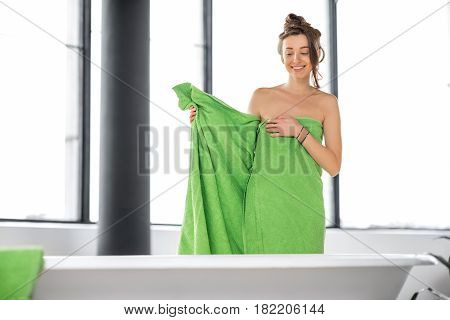 Beautiful woman in green towel prepairing for bathing in the bathroom