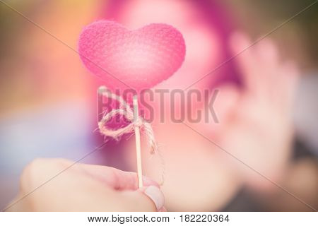 ask for love man to give a pink heart to women hand ok at blur background