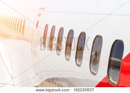 large heavy modern passenger widebody airplane side close up detailed exterior view with exit door handle, passenger windows, cargo door