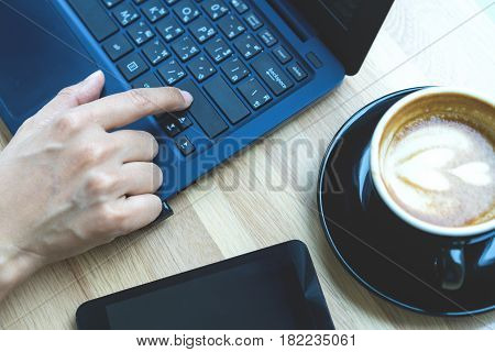 Businesswoman working with modern devices laptop computer and mobile phone in coffee shopwoman's hands using laptop in interior woman at her workplace using technology .
