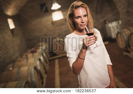 Beautiful woman oenologist tasting wine in winegrower cellar