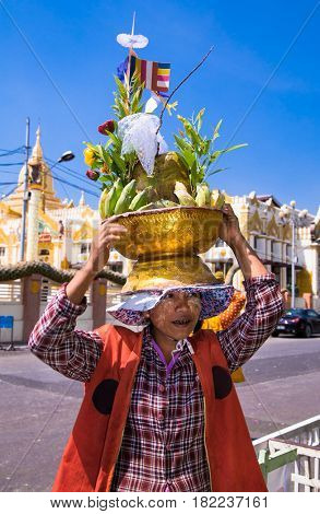 YANGON, MYANMAR -MARCH 3, 2017: Woman wears on his head baskets of green bananas and coconuts for donation at Botataung Pagoda in Yangon, Myanmar. (Burma)