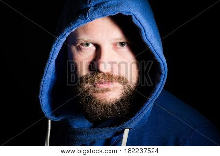 Solid bearded middle-aged man in a hood  portrait on black background