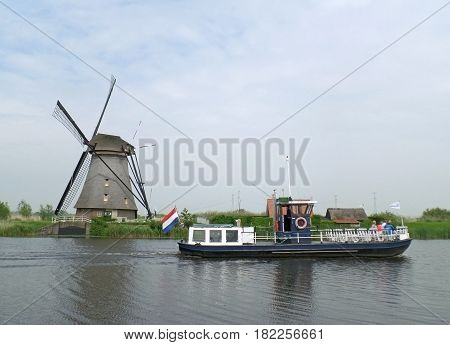 Traditional Dutch Windmill and Sightseeing Boat on the canal of Kinderdijk, Molenwaard, Netherlands