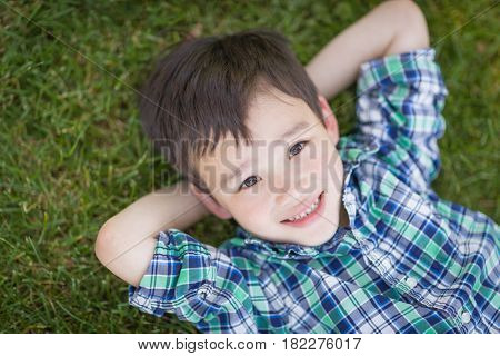 Mixed Race Chinese and Caucasian Young Boy Relaxing On His Back Outside On The Grass