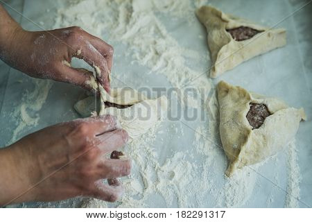 Baking peremech concept. Flour, dough and meat cooking ingredients. Hands top view of cooking belyash cuisines. ground meat with hole wrapping