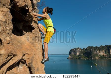 free solo woman rock climber climbing at seaside cliff