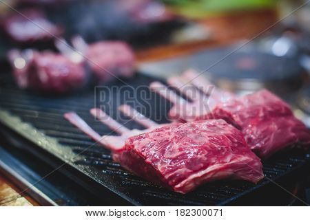 Different stages of cooking the steak on a kitchen, barbeque, roasted lamb ribs, big dish plate with roasted full pork head, served in restaurant with vegetables, lamb, ham and chicken.