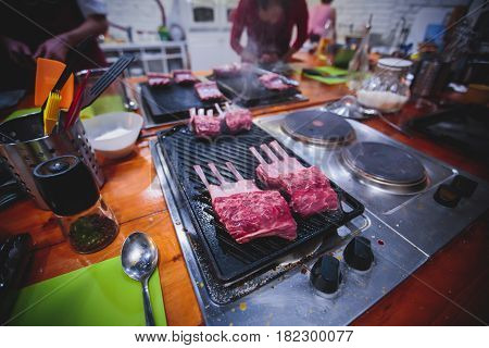 Different stages of cooking the steak on a kitchen, barbeque, roasted lamb ribs, big dish plate with roasted full pork head, served in restaurant with vegetables, lamb, ham and chicken.