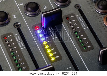 Close up shot of a DJ mixer volume faders with volume levels in the red