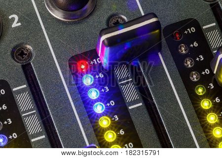 Close up shot of a DJ mixer volume faders with volume levels in the red