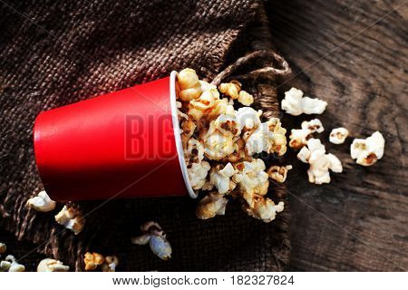 Fresh Popcorn in a red cardboard box on the wooden table Cinema concept