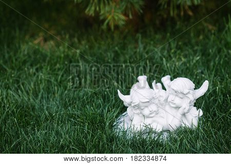 Close up of white figurine of two angels with green grass background