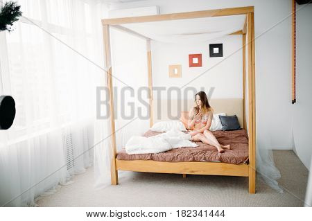 Beautiful Naked Pretty Sensual Brunette Girl Sitting On The Bed And Looking Out The Window At The Mo