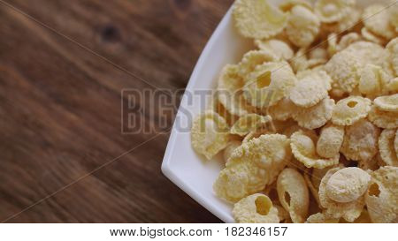 Corn flakes in white bowl with copyspace to the left. Concept of breakfast.