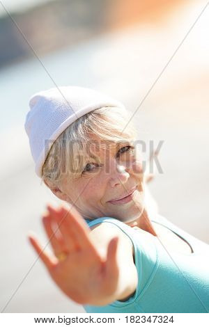 Senior blond woman doing yoga exercices on the beach